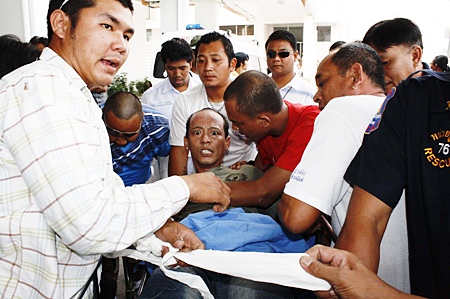 After subduing an irate Suparit from the streets, rescue workers return him to the hospital for treatment.